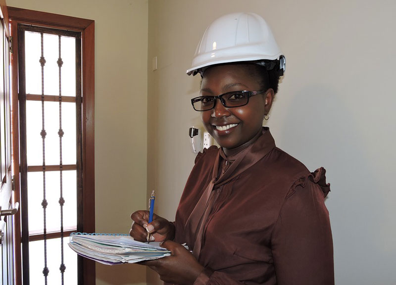 woman in white hard hat writing on paper 