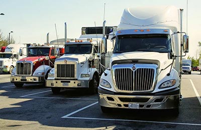 four 18-wheeler trucks parked in a parking lot